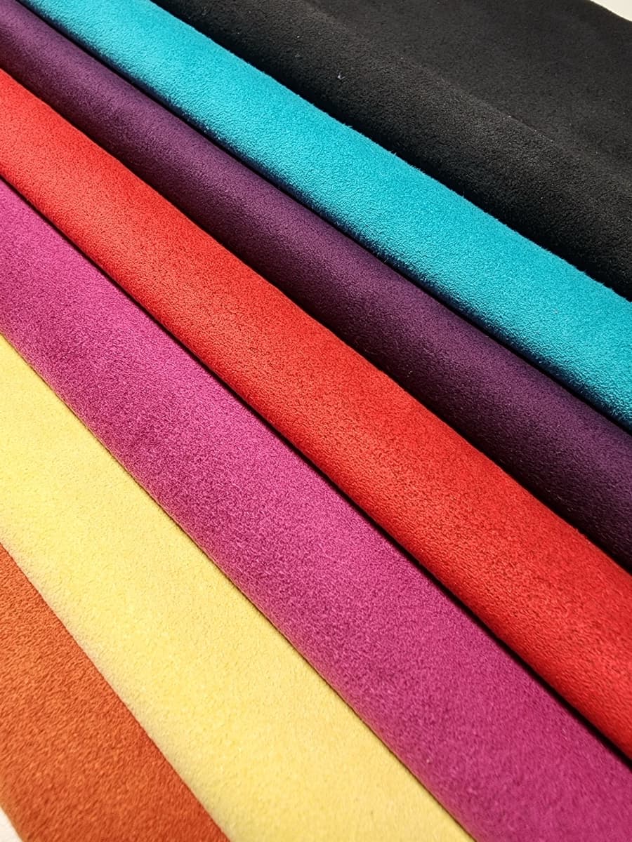 Rolls of Ultrasuede in black, teal, purple, red, magenta, yellow and orange